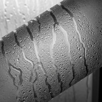 Close up black and white abstract view of condensation droplets forming patterns on a textured surface photo