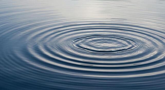 Concentric ripples expanding outward on a calm water surface creating a mesmerizing circular pattern photo