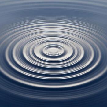 Concentric ripples emanating from a central point on a smooth dark surface creating a mesmerizing abstract pattern photo