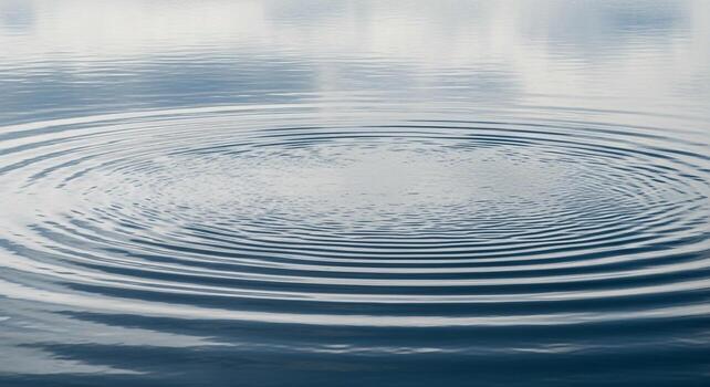 Concentric ripples expanding across a calm water surface creating a mesmerizing pattern of waves photo