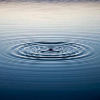 Concentric ripples expand across a calm blue water surface creating a serene and meditative visual effect photo
