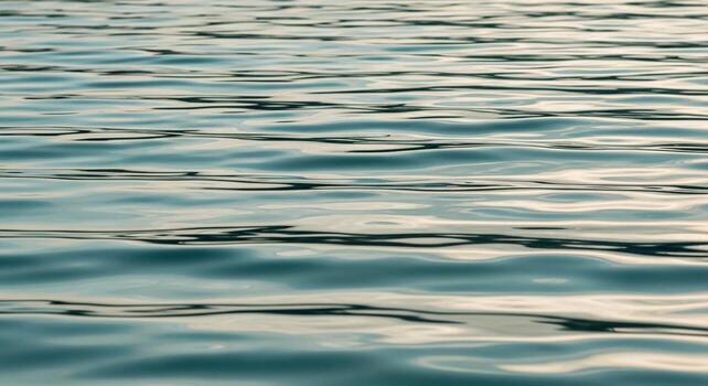 Close up view of gentle rippling water surface reflecting soft diffused light creating abstract patterns and serene blue green hues photo