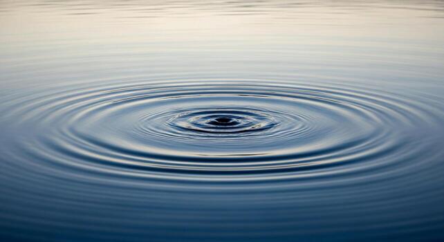 Concentric ripples emanating from a single drop on a calm water surface creating a mesmerizing circular pattern photo