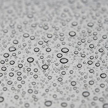 Close up macro view of numerous small water droplets scattered across a textured gray surface creating a natural abstract pattern photo
