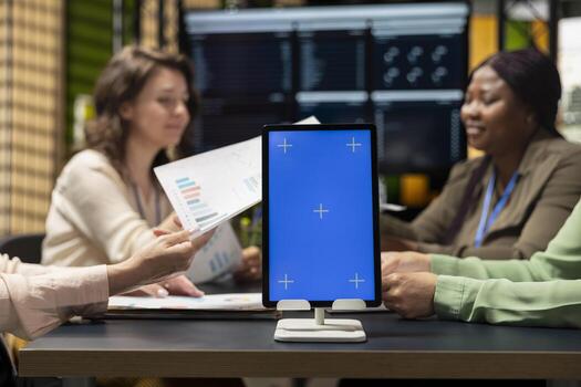 Group of diverse colleagues gathering near isolated copy space on tablet in boardroom, perfect for custom organizational graphics, finance charts or analytics overlays for performance reports. photo