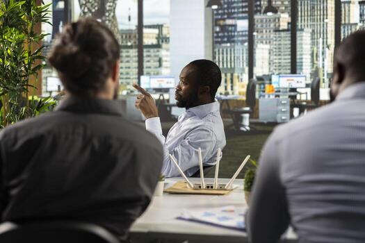 Work team engaged in negotiation and project consulting during business meeting. Employees use laptops to analyze finance data, metrics, and performance reports in a dark office setting. photo