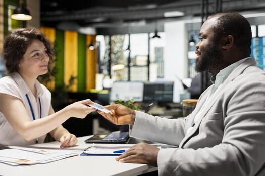 Interviewer handing workplace badge to new hire after the recruiting process, completing registration with ID confirmation on credentials for the role within the corporate office system. photo