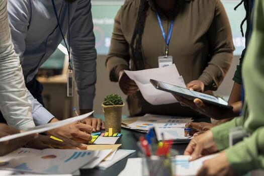 Multiethnic forecasting team reviewing report files during important meeting, updating project agenda and discussing business development with shareholders in office after hours. photo