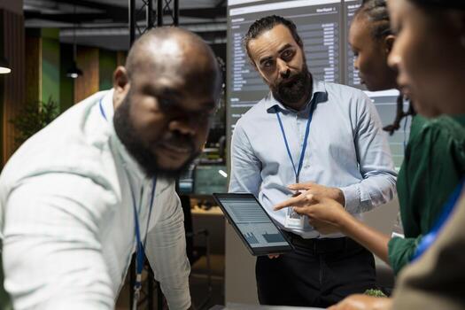 Diverse coworkers team engaging in after hours collaboration during meeting, reviewing statistics and projections while sharing files and providing feedback on finance objectives. Business intel. photo