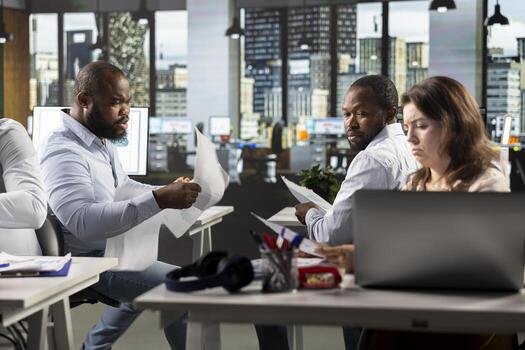 Diverse coworkers in office working on analytics and forecasting. Professional staff review visual data, diagrams, and documentation to enhance management and business objectives. photo