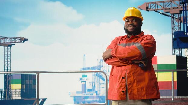 Portrait of happy drilling barge engineer using walkie talkie enabling quick responses coordination required. Cheerful man on oil platform deck listening to reports through radio transceiver, photo