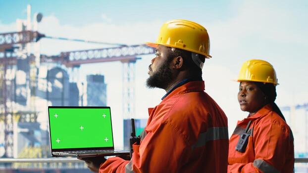 Green screen mockup laptop software used by drilling rig experts for anomaly detection. Offshore platform employees use chroma key notebook device application to control systems remotely photo