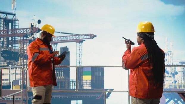 Offshore platform specialist using portable radio device to monitor systems during operations. Drilling rig technician using walkie talkie, doing emergency procedures, calibrating equipment, photo