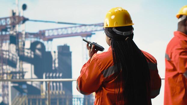 Offshore platform specialist using portable radio device to monitor systems during operations. Drilling rig technician using walkie talkie, doing emergency procedures, calibrating equipment photo