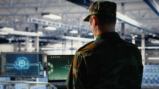 Military data center specialist using radar software on laptop to watch for enemy threats. Army soldier in data center scans suspicious activity to detect dangers using notebook, camera B photo