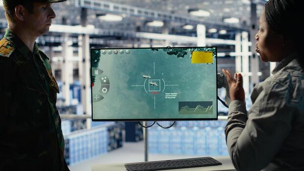 Military data center coworkers looking at radar software on screen to watch for enemy threats. Team of army employees in data center scans suspicious activity to detect dangers, camera B photo