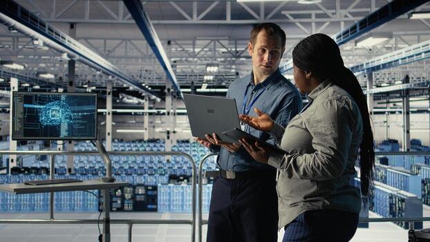 Technicians working together in server room, optimizing deep learning AI systems handling tasks. Data center coworkers doing brainstorming to adjust artificial intelligence model parameters, camera A photo