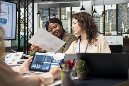 Group of business associates meeting in boardroom to align performance goals with project indicators, surrounded by reports and digital tools. Ambitious team showcasing collective success. photo