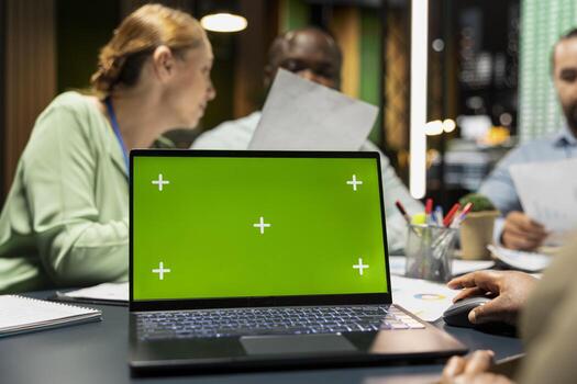 Workers group reviewing insights with chroma key after hours, analyzing annual trends and collaborating on project agenda supported by visual data. Business intel projections in a meeting. photo