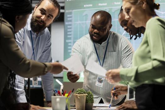 Night time meeting unfolds as a multiethnic team gathers in a strategy room, analyzing visual data, statistics and risk assessment files to drive project development forward for efficiency. photo
