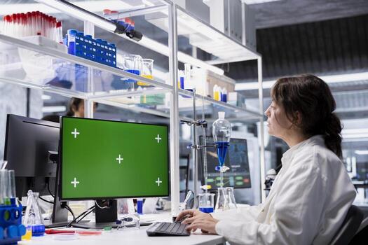 Lab technician looking at 3D molecular model visualization on green screen computer monitor. Woman using bioengineering software on chroma key PC in medical lab displaying DNA data, photo