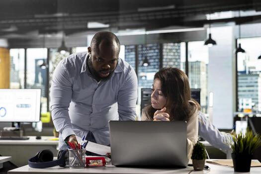 Professional business people analyze documents and graphs for risk assessment. Diverse work team collaborating on report writing, forecasting and performance metrics in modern office. photo