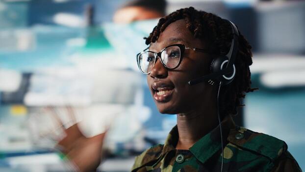 Close up of army telecommunications operator uses tablet and headset to manage secure military communications. Soldier coordinates mission support from command center with surveillance technology photo