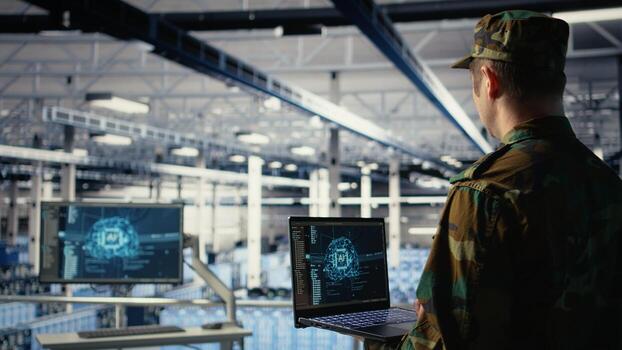 Army programmer in high tech server hub uses AI application on laptop to review reconnaissance information. Data center IT expert wearing military uniform uses AI on notebook to plan mission, camera A photo