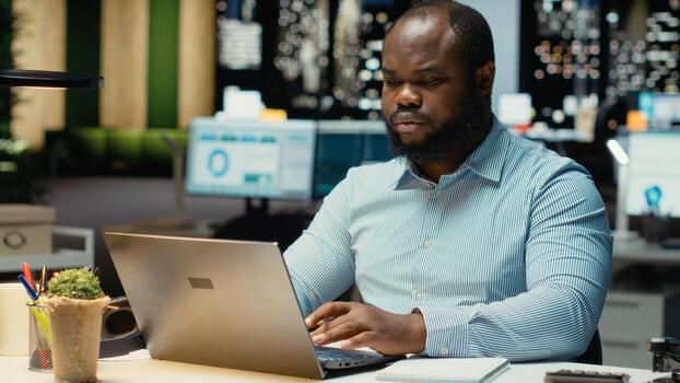 Male finance analyst after hours fact checking and transcribing documents, writing important data on his laptop. Creating a summary and designing strategy to align with company targets. photo