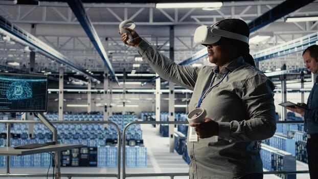 Software developer in server room wearing VR goggles optimizing deep learning systems handling tasks. African american woman in data center adjusts AI model parameters using virtual reality, camera A photo