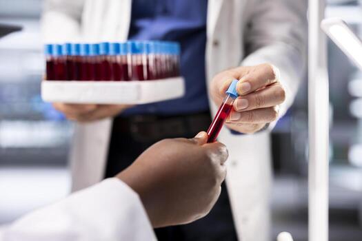 Close up of researchers collecting blood samples in flasks on tray, handling procedure with test tubes in laboratory. Team of experts conducting diagnostics and biology experiments. photo