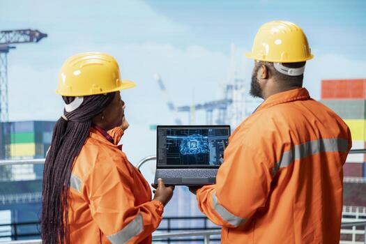 Offshore platform engineers use artificial intelligence software on laptop to optimize drilling operations. Crew monitors barge activity using automated AI performance tracking system photo
