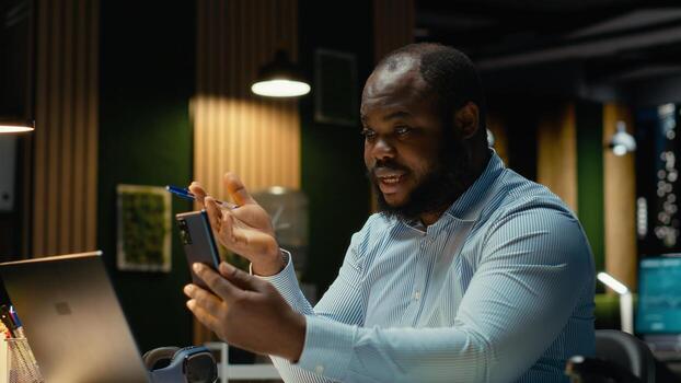 Businessman interacting with staff during conference on smartphone, sharing latest report data for a briefing session. Collaborative meeting on web call after hours. photo
