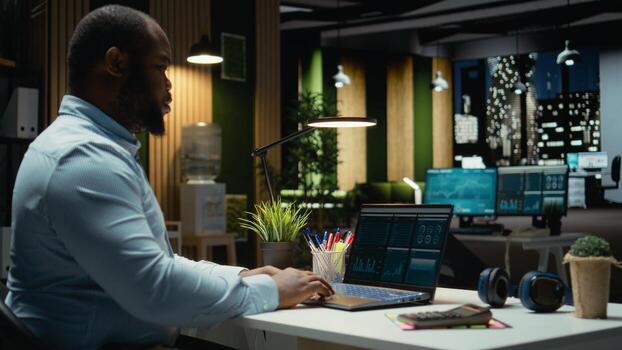 Male finance analyst reviews trading accounts and archived data for revenue reports, using digital graphs to plan resources allocation and align business targets with financial success. photo