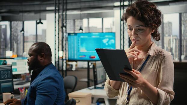 Female office administrator using digital tools for KPI analytics to build a new vision, review performance data insights on tablet for goals achievement in a modern office environment. photo