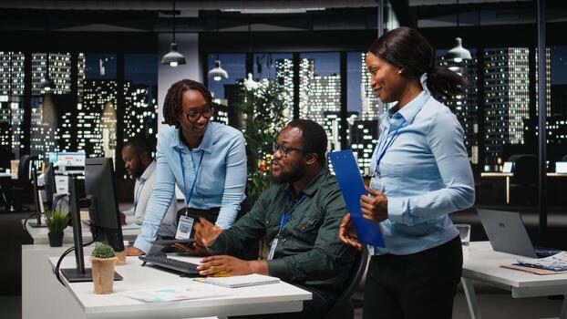Two black workers reviewing data insights on pc in professional workspace, developing business solutions with strategy planning and performance metrics analysis for goals achievement. photo