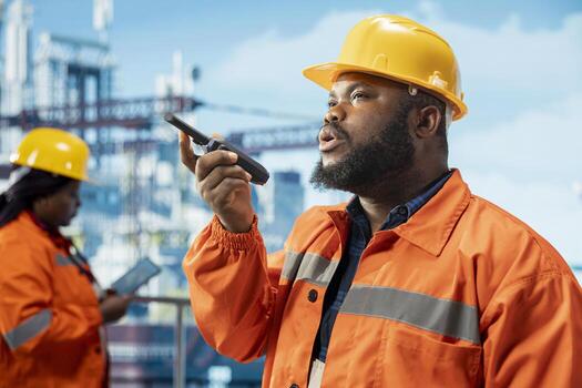 Drilling barge engineer uses walkie talkie enabling quick responses coordination required for working in dangerous conditions. Man listens to status report through handheld radio transceiver photo