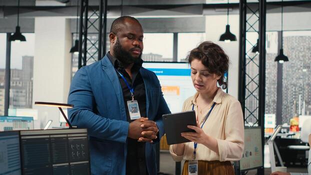 Two employees reviewing data insights on tablet in professional workspace, developing business solutions with strategy planning and performance metrics analysis for new goals achievement. photo