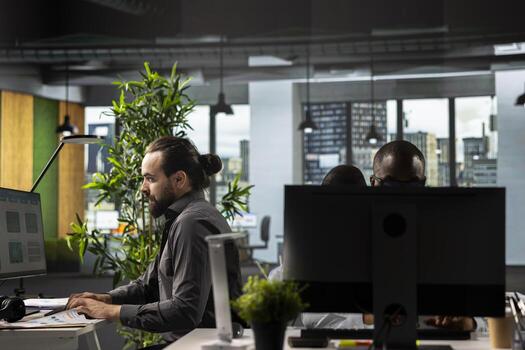 Business colleagues reviewing files and charts during a strategy briefing. Employees in a multinational company share insights and coordinate tasks using pc and visual data tools. photo