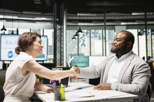 Recruiter and confident applicant sharing handshake after successful interview, confirming the start of employment, onboarding and agreement on the terms of the contract within hiring process. photo