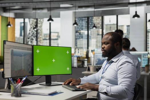 RD expert studies wind turbine technologies on chroma key PC to accelerate clean energy adoption. African american man optimizes aerodynamic design of wind turbine using mockup computer photo