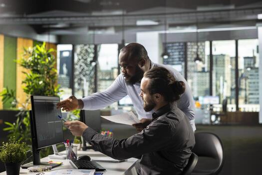 Diverse colleagues team in a multinational company reviews analytics, diagrams and performance metrics. Business people sharing insights and projections to enhance corporate planning. photo