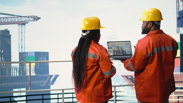 Offshore platform employees use performance management software to observe operations. Crew uses laptop program integrating sensor readings to manage industrial barge operations, photo