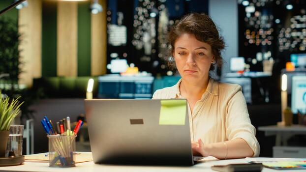 Female employee proofreading a document before transcribing on notebook, handwritten notes on paper after hours. Woman engaged in documenting important ideas from archived report. Camera B. photo
