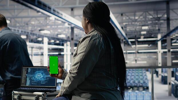 Data center admin uses isolated screen smartphone while deploying machine learning tech. Server room IT expert uses chroma key phone while training artificial intelligence systems with datasets photo