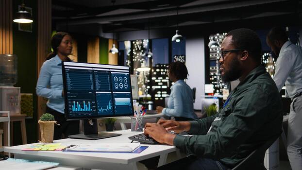 Male office worker using data and technology for business management, reviewing statement graphs on monitor to create reports and improve efficiency, objectives achievement. Vision. photo