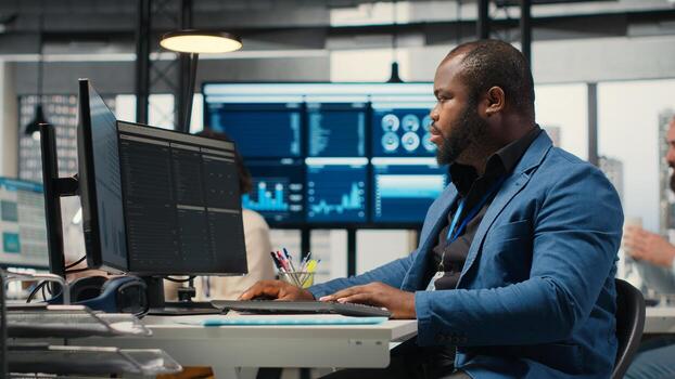 African american male analyzing financial data forecast on a computer, developing innovative business solutions for alignment with corporation objectives. Professional environment. photo