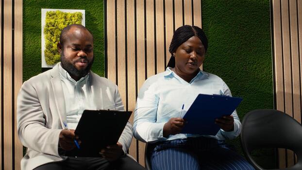 Black candidates in a hallway receive files to fill in while they wait, registration forms and CV resumes for the ongoing recruitment process. Participating in process and waiting to start. photo