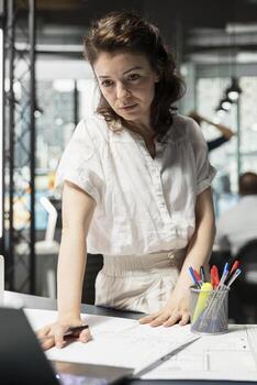 Real estate developer adjusting construction blueprints with 3D software and design tools, using laptop and plans. Woman aligning the project with zoning laws and infrastructure goals. photo