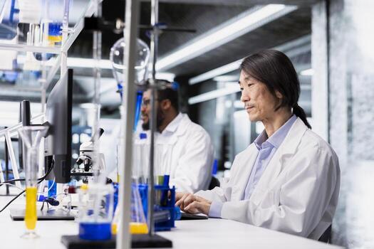 Senior laboratory technician using computer application for DNA data analysis. Asian research facility worker using bioinformatics genomics software on PC in modern lab environment photo